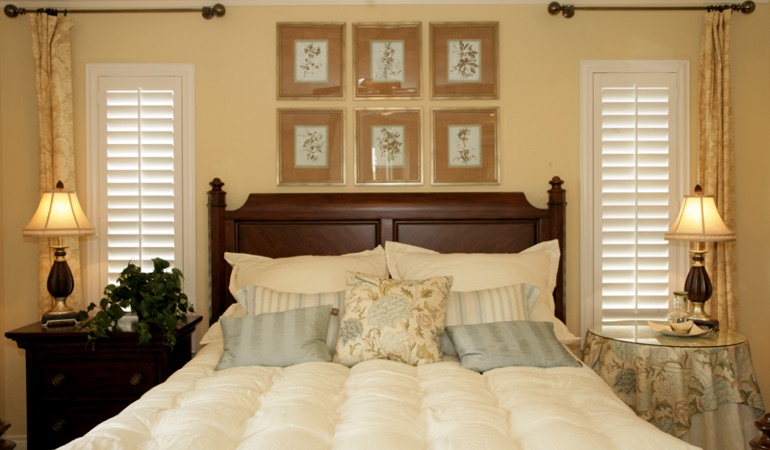 Beige bedroom with white plantation shutters covering windows in Fort Myers 